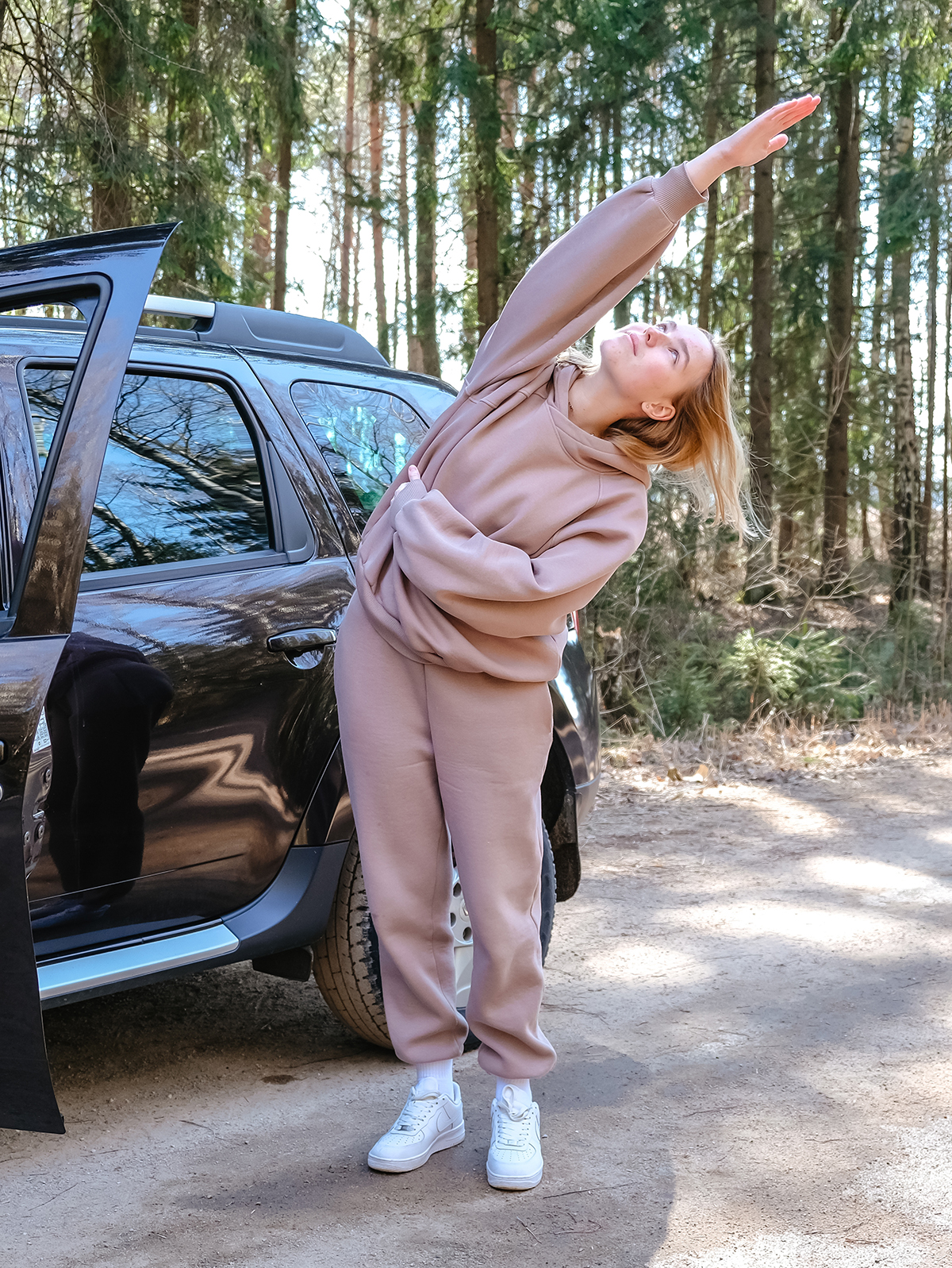 Eine Frau in braunem Trainingsanzug macht Dehnuebungen 