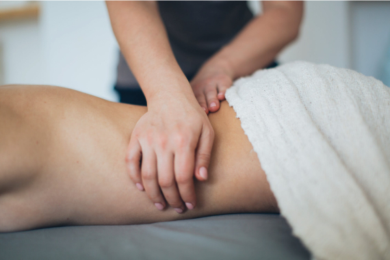 Eine Person liegt auf einer Massagebank und wird von einer anderen massiert Eine Person liegt auf einer Massagebank und wird von einer anderen massiert