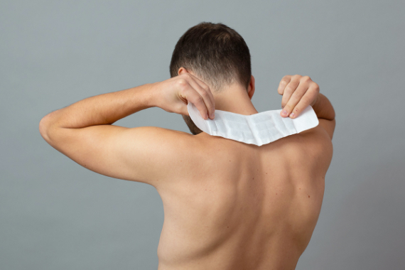 Mann mit freiem Oberkörper fixiert ThermaCare® Wärmepflaster am Nacken Mann mit freiem Oberkörper fixiert ThermaCare® Wärmepflaster am Nacken