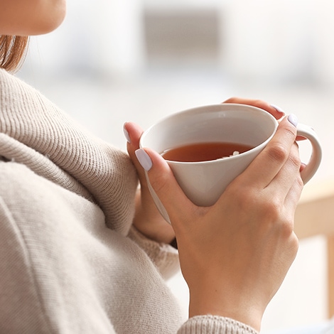 Frau hält eine Tasse Tee in den Händen Frau hält eine Tasse Tee in den Händen