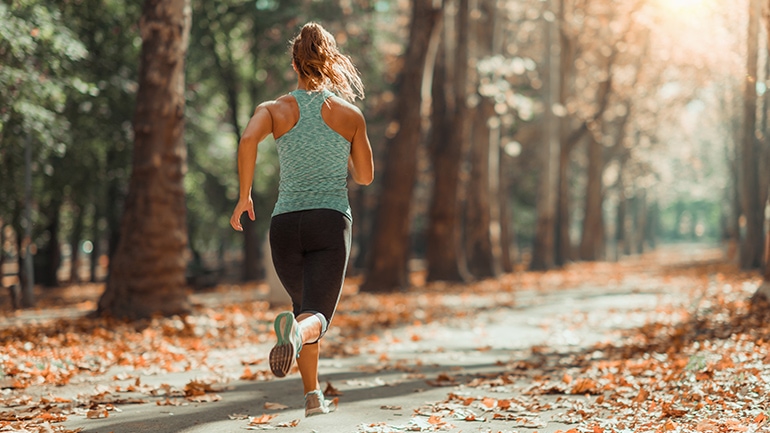 Frau joggt einen Waldweg entlang Frau joggt einen Waldweg entlang